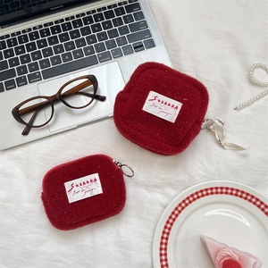 Detailed view of red plush coin purses with zipper and metal ring on a cozy desk setup