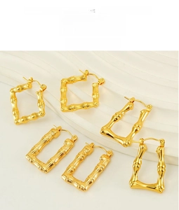 Detail view of gold-plated bamboo texture earrings in square and U-shaped geometry
