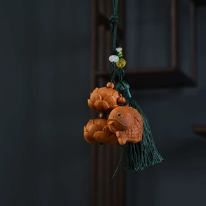 Detail of hand-carved wood fish and lotus pendant with a silky deep green tassel decoration