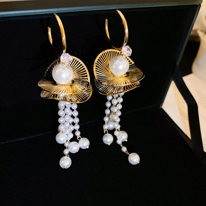 Macro detail of gold tassel earrings featuring large white pearls and clear zircon accents