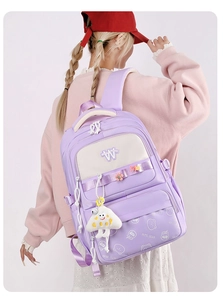 Detail view of purple school backpack with cute cloud charm on a model's back
