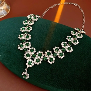 Close-up of sparkling sunflower pendant with green gemstone on dark velvet pad