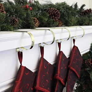 Close-up of golden metal Christmas stocking hooks on a festive white fireplace mantel