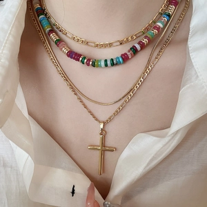 Detail of 18k gold plated layered cross necklace featuring colorful beads and Figaro chains