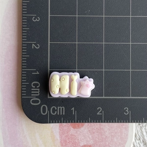 Macro shot of 1.8cm purple resin 'Hi' charm with star on a centimeter measuring mat