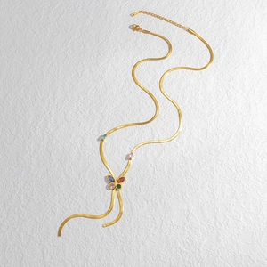 Detail of gold snake chain necklace with butterfly pendant and colorful gemstones