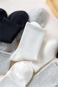 Close-up of stacked cotton rib knit socks in black, white, and grey color options