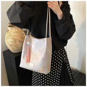 Detail of light pink floral shoulder bag with silk texture and decorative fringe tassel