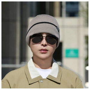 Detail of light grey knit beanie featuring black stripes and a woven logo label