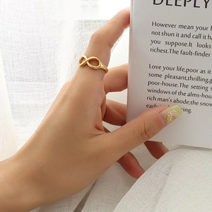 Detail of a gold infinity ring on a finger, featuring a French vintage aesthetic design