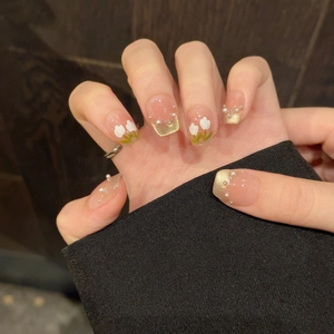 Détail de faux ongles tulipes avec french manucure œil-de-chat dorée et perles