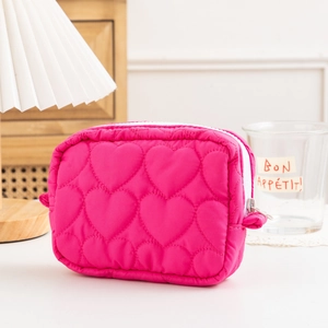 Detailed close-up of rose pink quilted heart cosmetic bag with white zipper closure