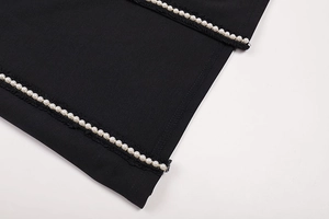 Detail shot of elegant white pearl embellishments on premium black lace dress fabric