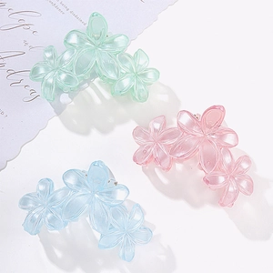 Three 3D flower hair claws in pastel pink, green and blue on a clean white background