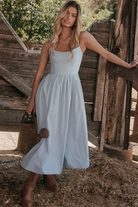 Close-up of light blue backless sundress with delicate straps in a rustic farm setting