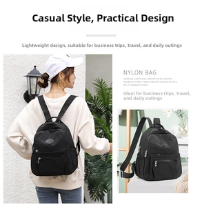 Detail of a casual black nylon backpack featuring front zipper pocket and side elastic pouches