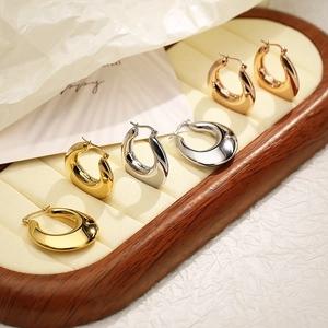 Macro shot of U-shaped minimalist earrings in gold, silver, and rose gold mirror finish