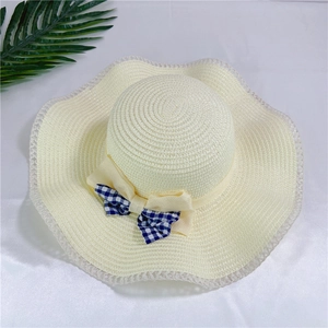 Dettaglio della tesa del cappello di paglia con elegante fiocco a quadretti blu