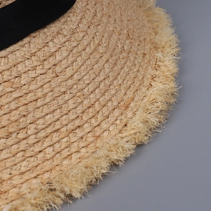 Detailansicht der Raffia-Strohhut-Struktur mit schickem Fransenrand und schwarzem Band