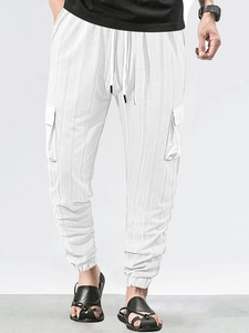 Detail of white cargo pants featuring textured check pattern and drawstring elastic waist