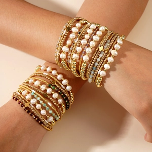 Set of four stacked bracelets with gold beads, pearls, and colorful stone cross pendants