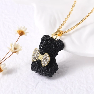 Dettaglio della collana placcata oro con ciondolo a forma di orso nero e fiocco lucido