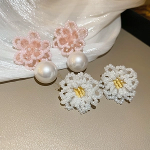 Detailed close-up of pink flower and white daisy beaded earrings on silk background