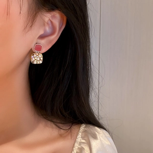 Detailed close-up of retro square earrings with pearls and red enamel on model