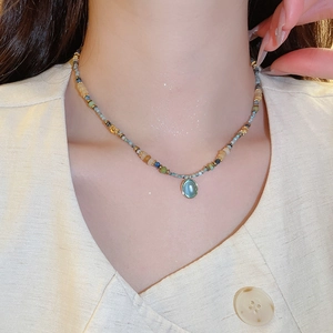 Close-up of a beaded stone necklace with an oval turquoise pendant on a female neck