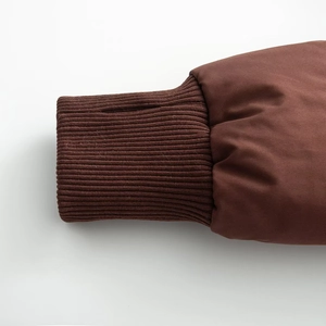 Detail of dark brown knit cuffs with functional thumb holes on padded winter jacket