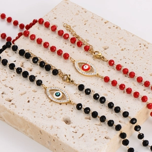 Red and black crystal beaded necklaces with gold devil eye charms on stone