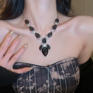 Close-up of luxury black teardrop gemstone necklace worn on neck with silver chain detail
