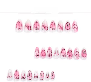 Detail of almond-shaped press-on nails with pink gradient, heart patterns, and pearls