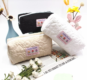 Three quilted heart cosmetic bags in black white and beige with pink Lucky Flower labels