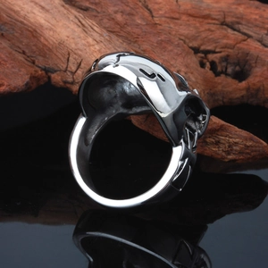 Side view of punk style stainless steel skull ring on a black reflective base