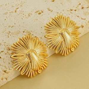 Golden flower and honeybee earrings in stainless steel on a beige stone surface