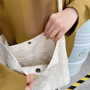 Detail of canvas tote bag showing daisy print, magnetic copper snap and inner pocket