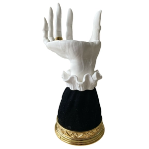 Detail of white resin witch hand tray with black velvet cuff and gold embossed base