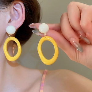 Nahaufnahme von Model mit gelben und weißen geometrischen Harzohrringen im minimalistischen Design