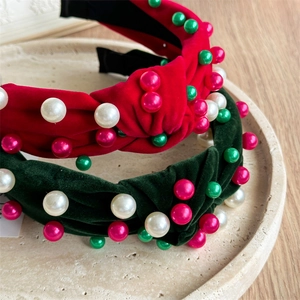 Détail de bandeaux en velours rouge et vert avec perles colorées sur un plateau beige