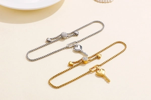 Détail de bracelets réglables avec clé en cœur doré et argenté et boucle en zircon