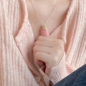 Detail of a minimalist gold geometric square pendant on a delicate link chain necklace