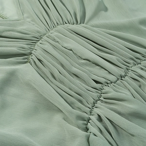 Detailansicht aus salbeigrünem Falten-Chiffon mit V-Ausschnitt und feinen radialen Falten