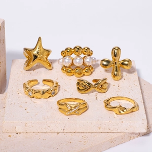 7-piece gold stainless steel ring set with pearl, starfish, and clover on stone display