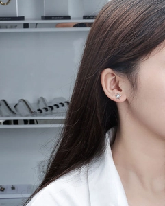 Close-up of a silver star-shaped stud earring with a central diamond zircon on an ear