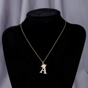 Close-up of gold letter A pendant with crown design and zircon stones on black velvet