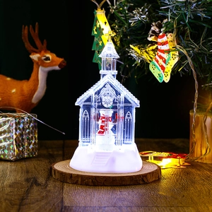 Macro shot of glowing Christmas church ornament with snowman figurine on wooden base