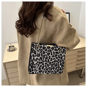 Detailed view of women's leopard print shoulder bag with gold chain strap on model