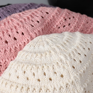 Close-up texture of hollow knit lace bucket hats in pastel pink and cream white
