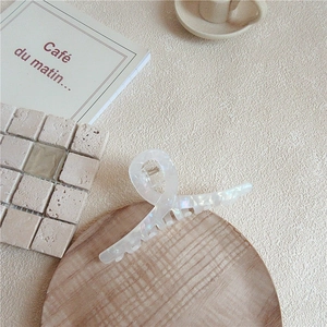 Elegant mermaid white acetate hair claw clip with rainbow pearlescent finish on wooden tray